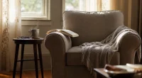 Tom fåtölj med filt vid fönster i eftermiddagsljus, symboliserar vila och reflektion